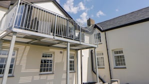 A two-story building with a balcony, windows, and a chimney. - Rosemary Cottage 2 (Tywyn)