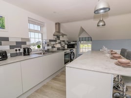 Una cocina moderna con una isla central, microondas, hervidor y pileta.