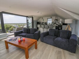 Una sala de estar moderna con una mesa de centro de madera, dos sofás grises y un balcón con vistas.
