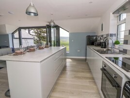 Una cocina moderna con una isla central, electrodomésticos integrados y vistas amplias a través de grandes ventanales.