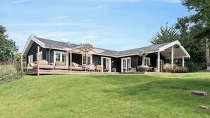 A house with a covered patio, outdoor seating, and a well-maintained lawn.