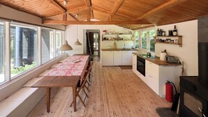A spacious kitchen with wooden floors, a dining area with a table, and a view through large windows.