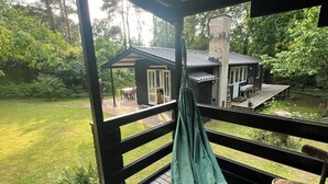 A covered deck with a hammock, a small building with a patio, and a stone chimney.