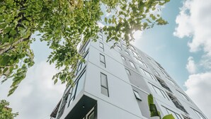 Ein modernes Gebäude mit zahlreichen Fenstern und Balkonen, umgeben von viel Grün.