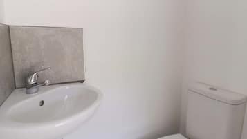 A bathroom with a white sink, a toilet, and a wall-mounted towel rack.