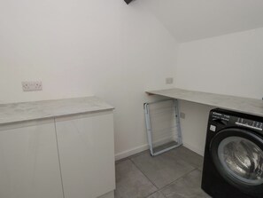 Une buanderie équipée d’un lave-linge, d’un étendoir et d’un plan de travail.