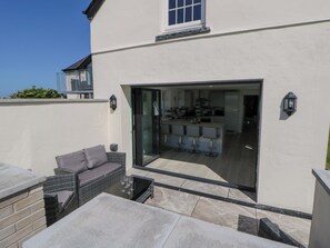 Une maison moderne dotée d’un patio, d’une porte vitrée donnant sur la cuisine et d’un balcon.