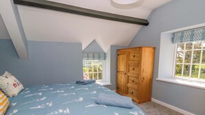 A bedroom with a bed, a wardrobe, a window, and a skylight. - Rosemary Cottage 1 (Tywyn)