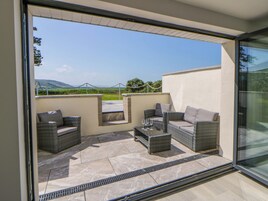 Un espacio moderno para sentarse al aire libre con muebles de mimbre y un ventanal que ofrece vistas panorámicas.