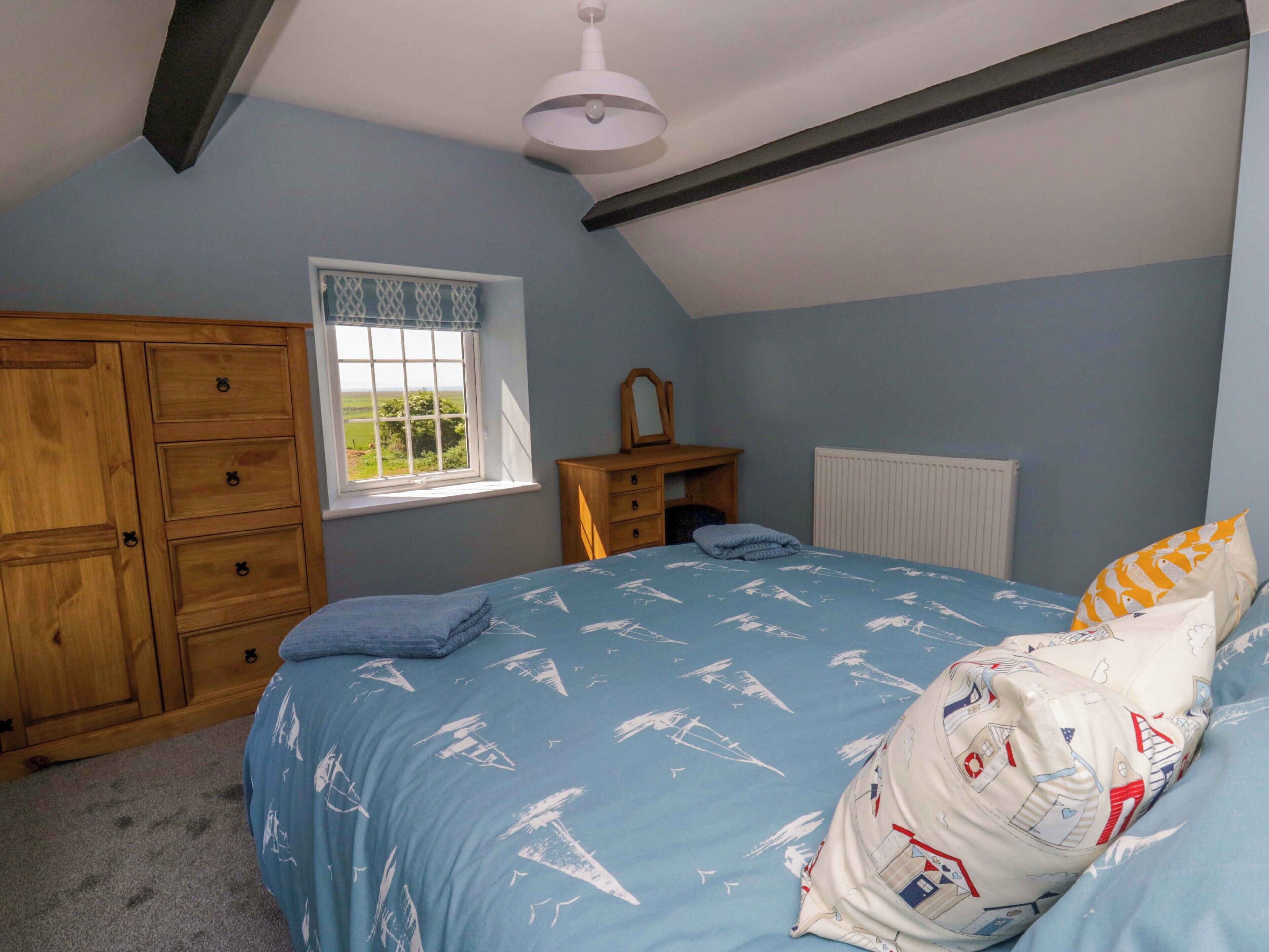Une chambre à coucher avec un lit, une armoire en bois, une fenêtre et un radiateur.