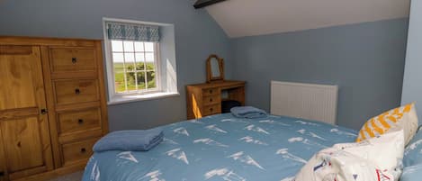 A bedroom with a bed, a wooden wardrobe, a window, and a radiator.