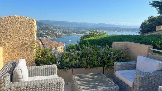 A terrace with wicker furniture, a view of a body of water, and distant mountains. - Sea view villa in Théoule-sur-Mer (Théoule-sur-Mer)