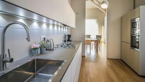 Ett modernt kök med rostfria vitvaror, ett trägolv och utsikt över matplatsen.