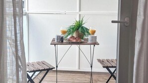 A small outdoor dining area with a table set for two, featuring a pineapple, a plant, and two glasses of orange juice. - New studio with terrace Airbus Aéroport (Colomiers)