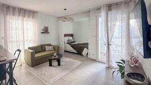 A modern living room with a sofa, coffee table, and a bed with a headboard. - New studio with terrace Airbus Aéroport (Colomiers)