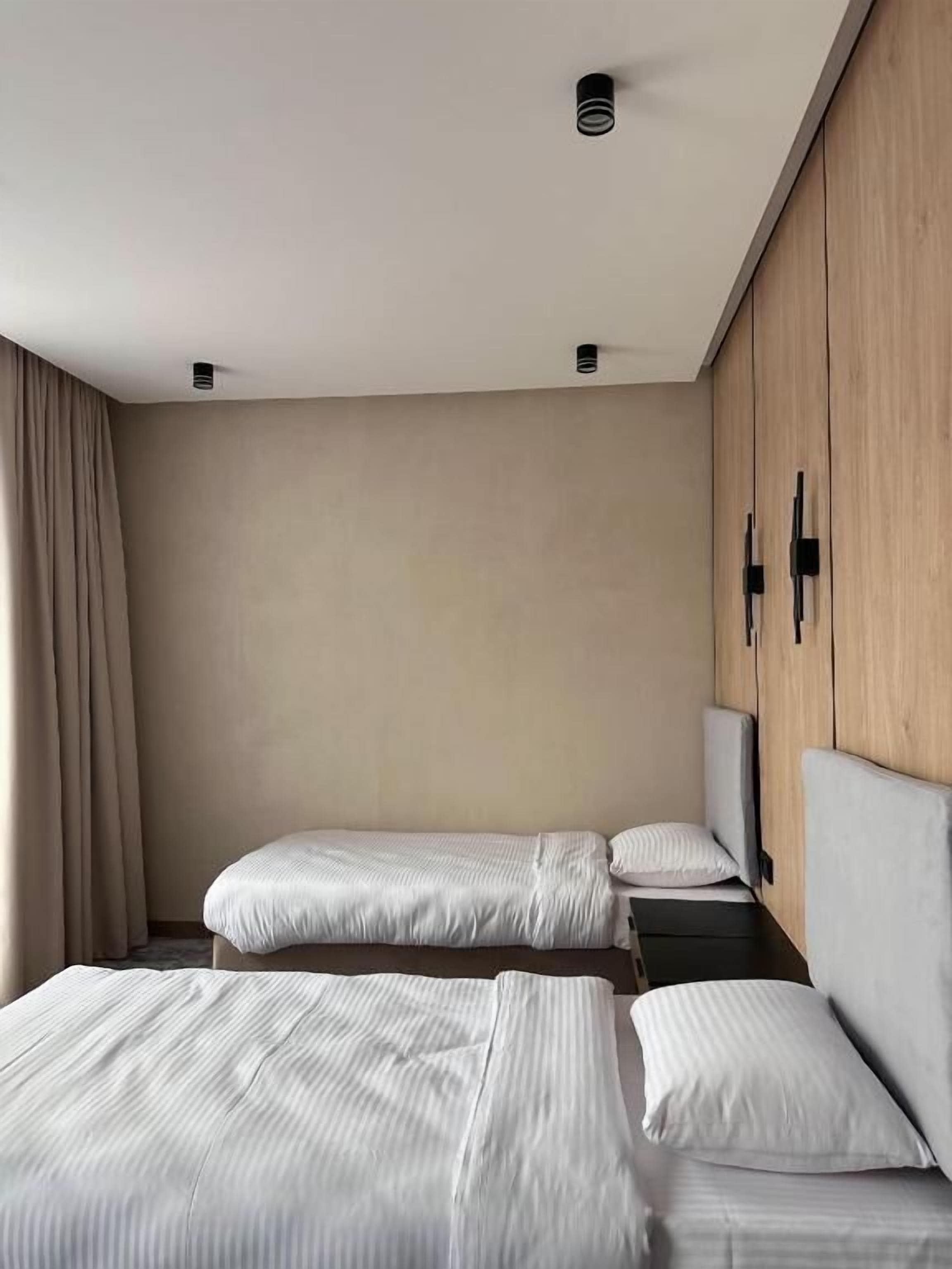 A hotel room with two beds, a wardrobe, and a window with curtains.