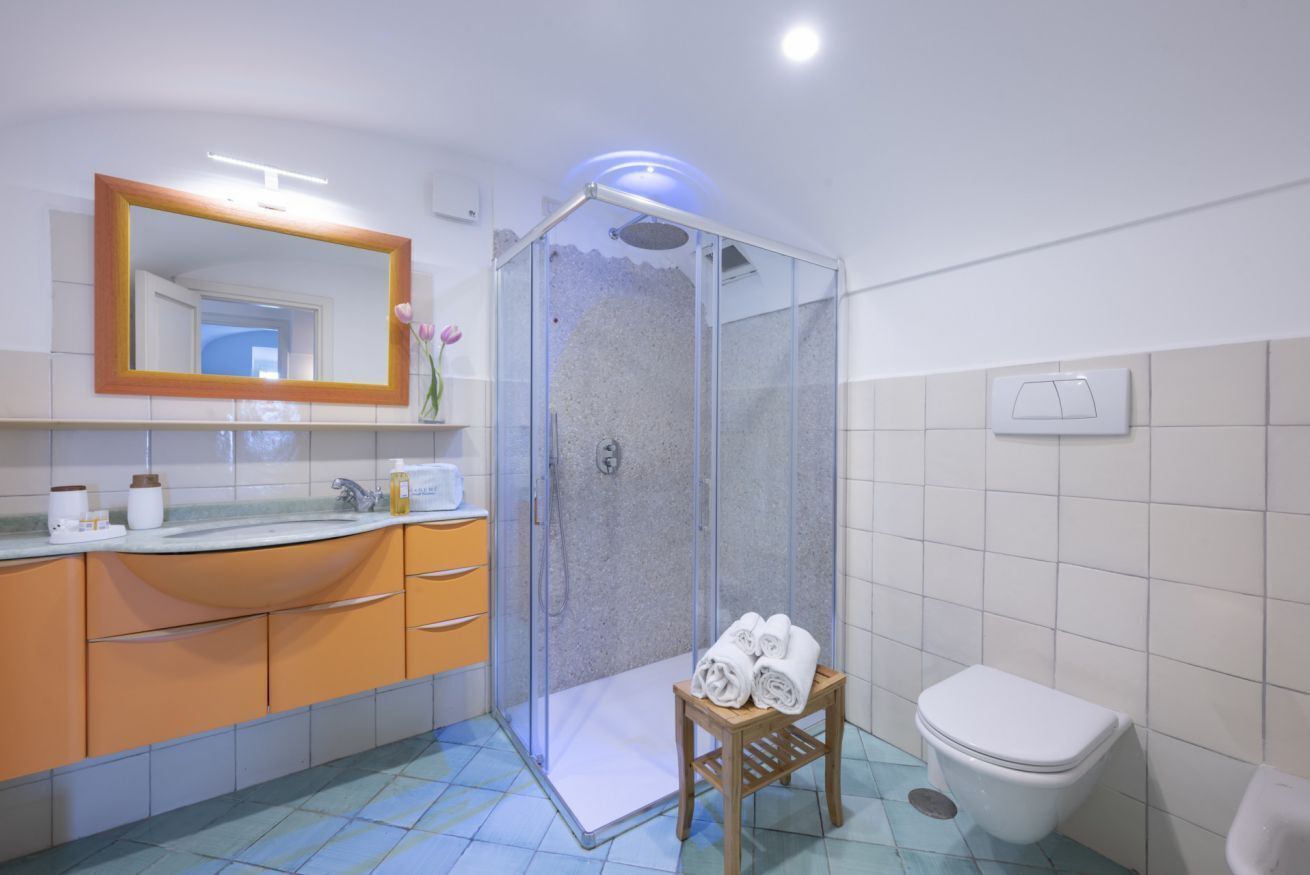 Ein Badezimmer mit einer Duschkabine, einem Waschbecken mit Spiegel und einer Toilette.