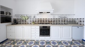Een keuken met witte kastjes, een kookplaat, een oven en een vaatwasser.