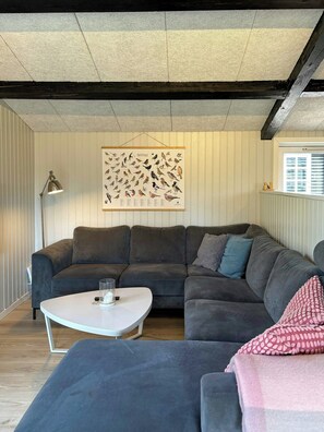 Ein modernes Wohnzimmer mit einer Eckcouch, einem Couchtisch und einer an der Wand befestigten Vogelillustration.