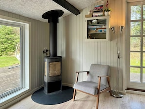 A room with a wood-burning stove, a chair, and a bookshelf.