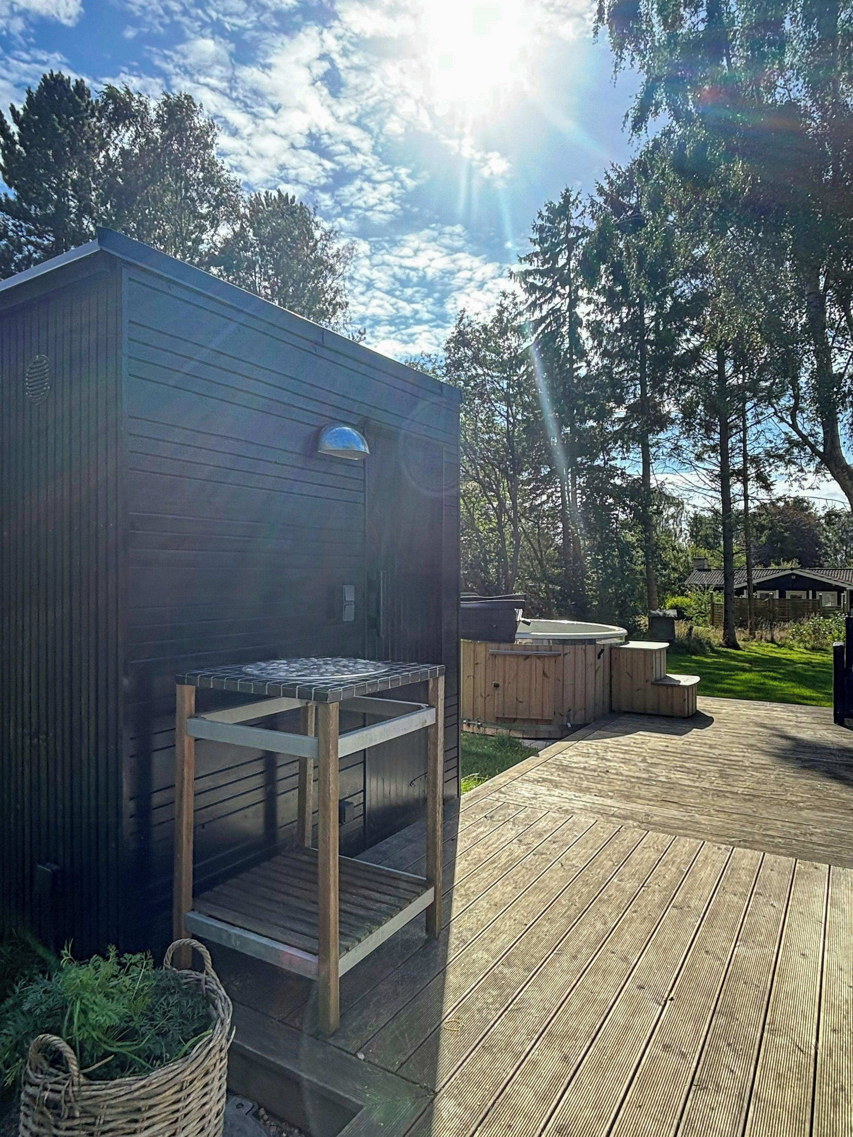 A wooden deck with a barbecue grill and a hot tub area.