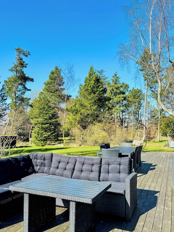 Eine Terrassenausstattung im Freien mit Korbmöbeln, darunter Sofas und ein Tisch.