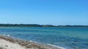 A clear blue sky over a calm body of water with a distant shoreline. - Summer house with wilderness bath by Kårup Forest (Fårevejle)