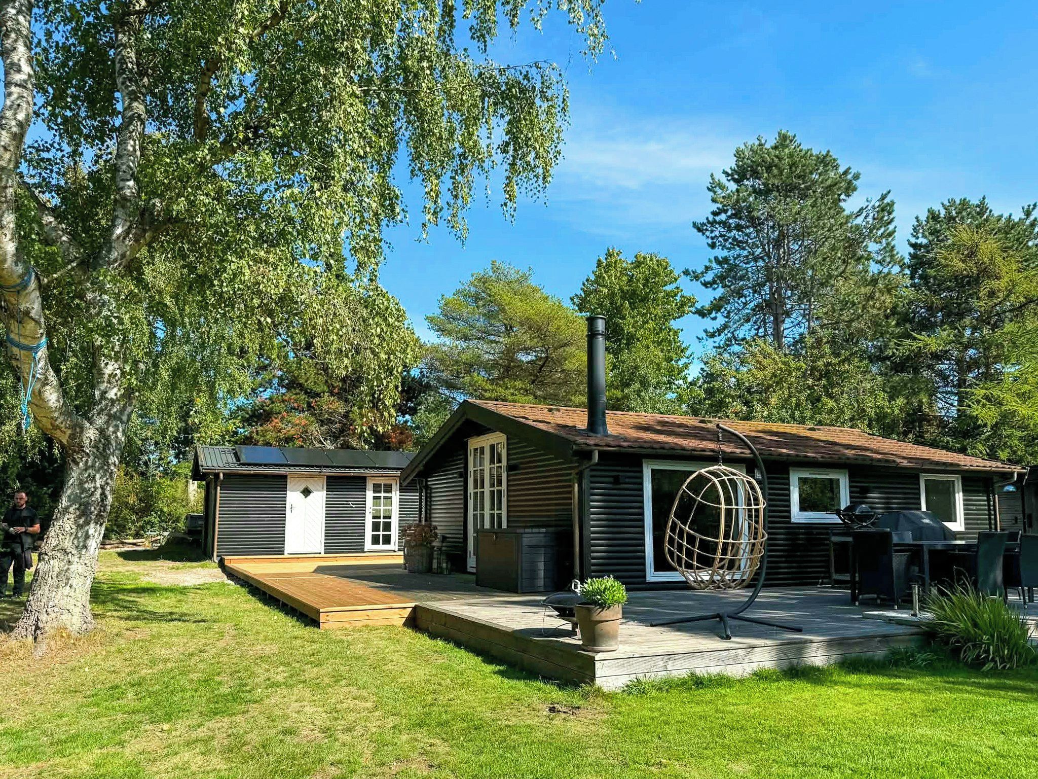 A cabin with a chimney, a porch, and a large window.