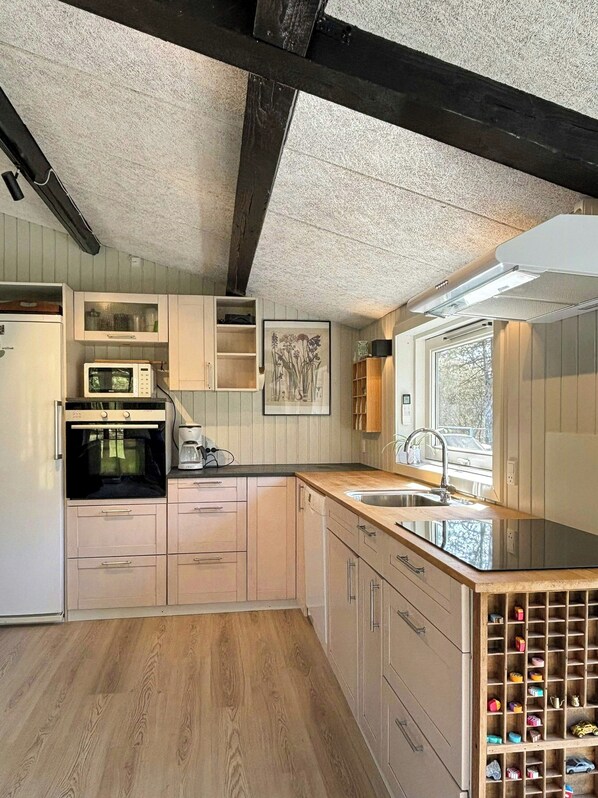 Eine Küche mit Holzausstattung, einer Mikrowelle, einem Backofen, einem Spülbecken und einem Fenster.