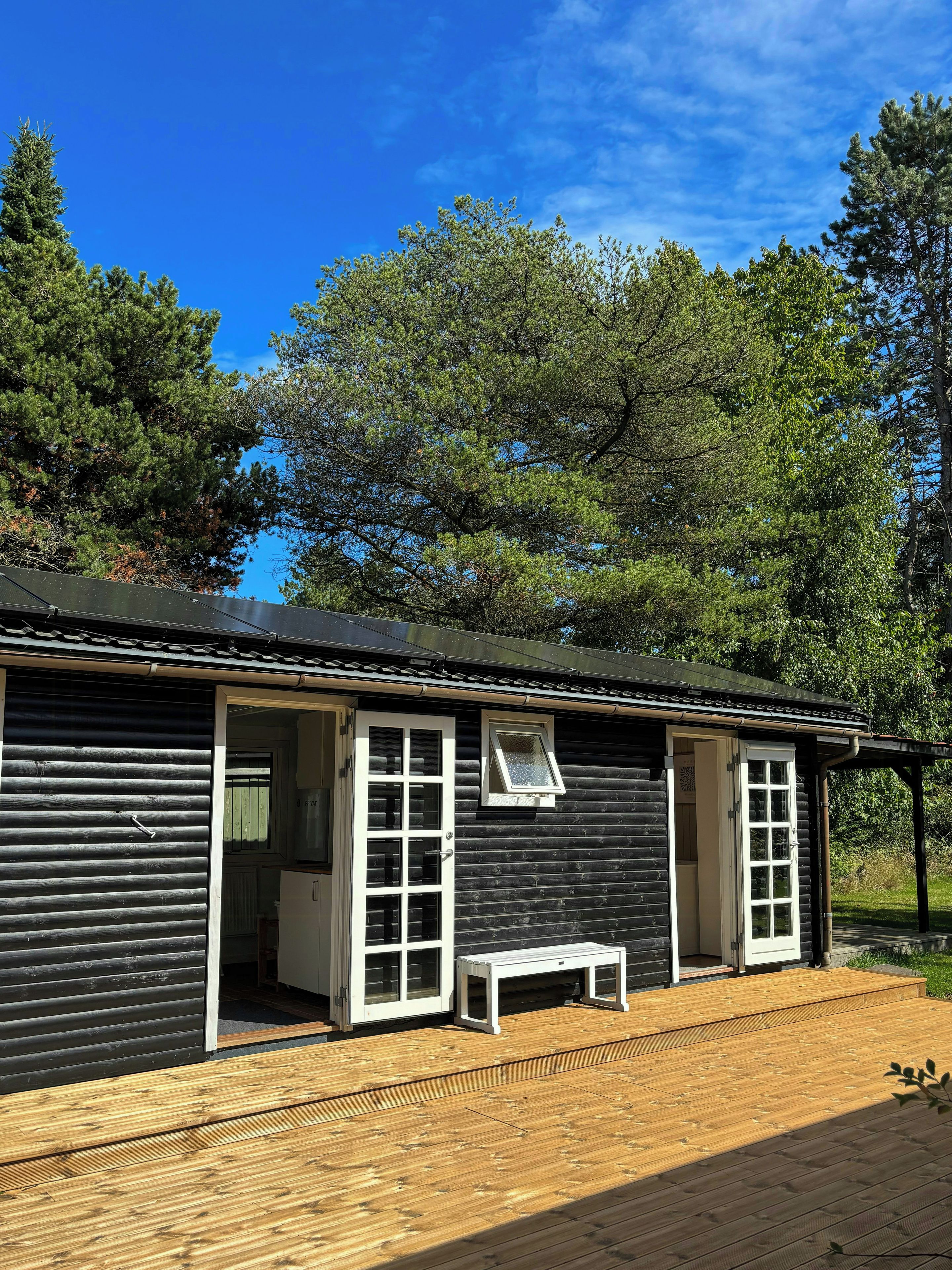 Une cabane dotée d’une terrasse en bois, d’un banc et d’une porte donnant sur un espace abrité.