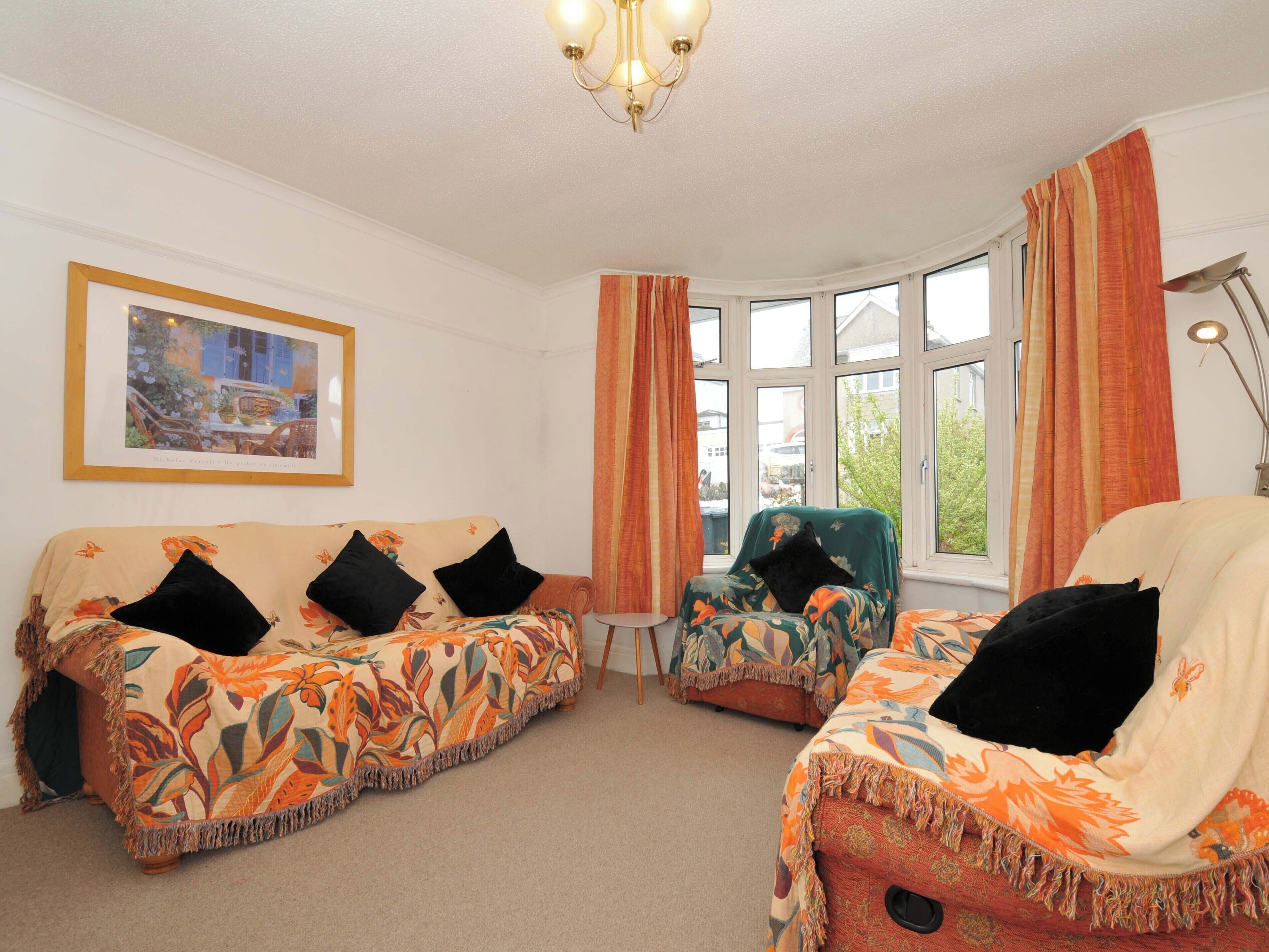A room with two sofas, a small table, and a chair with a view of the outside through large windows.