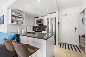 A modern kitchen with white cabinetry, stainless steel appliances, and a central island.