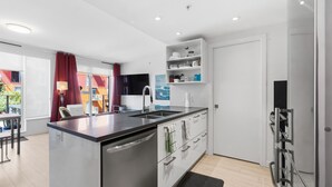 A modern kitchen with a central island, built-in shelves, and a large window. - Cozy condo with excellent views, 5 mins to arena (Vancouver)