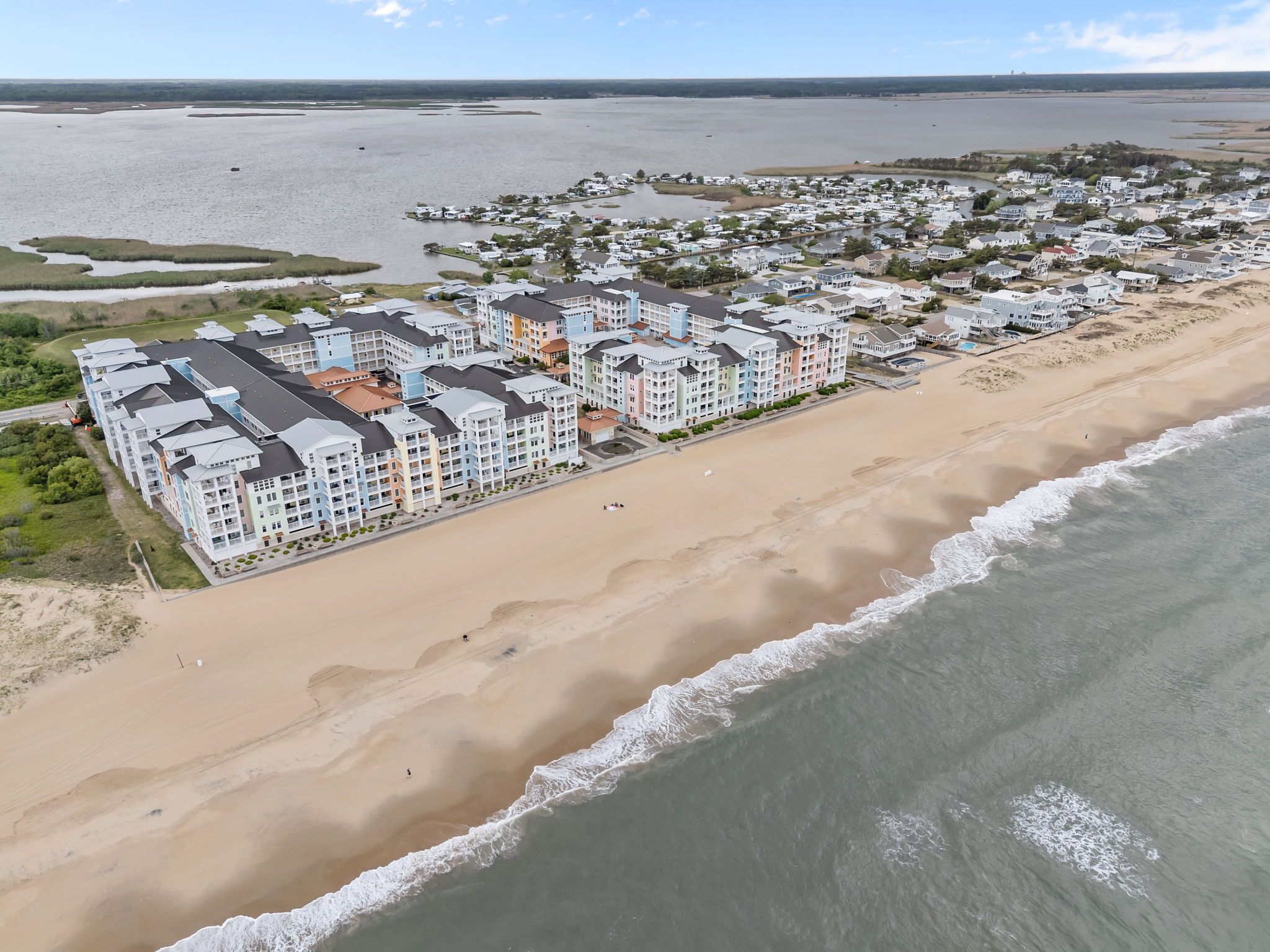 A coastal hotel with multiple buildings, a sandy beach, and a view of the ocean.