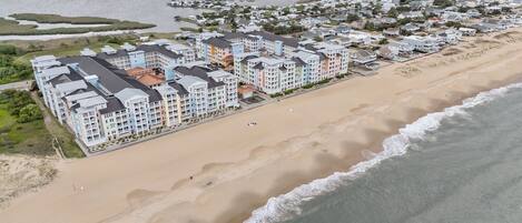A coastal hotel with multiple buildings, a sandy beach, and a view of the ocean.