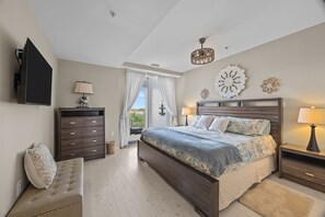 Ein Schlafzimmer mit Bett, Schminktisch, Bank, Fernseher, einer Kristallleuchtre und einem Fenster mit Vorhängen.
