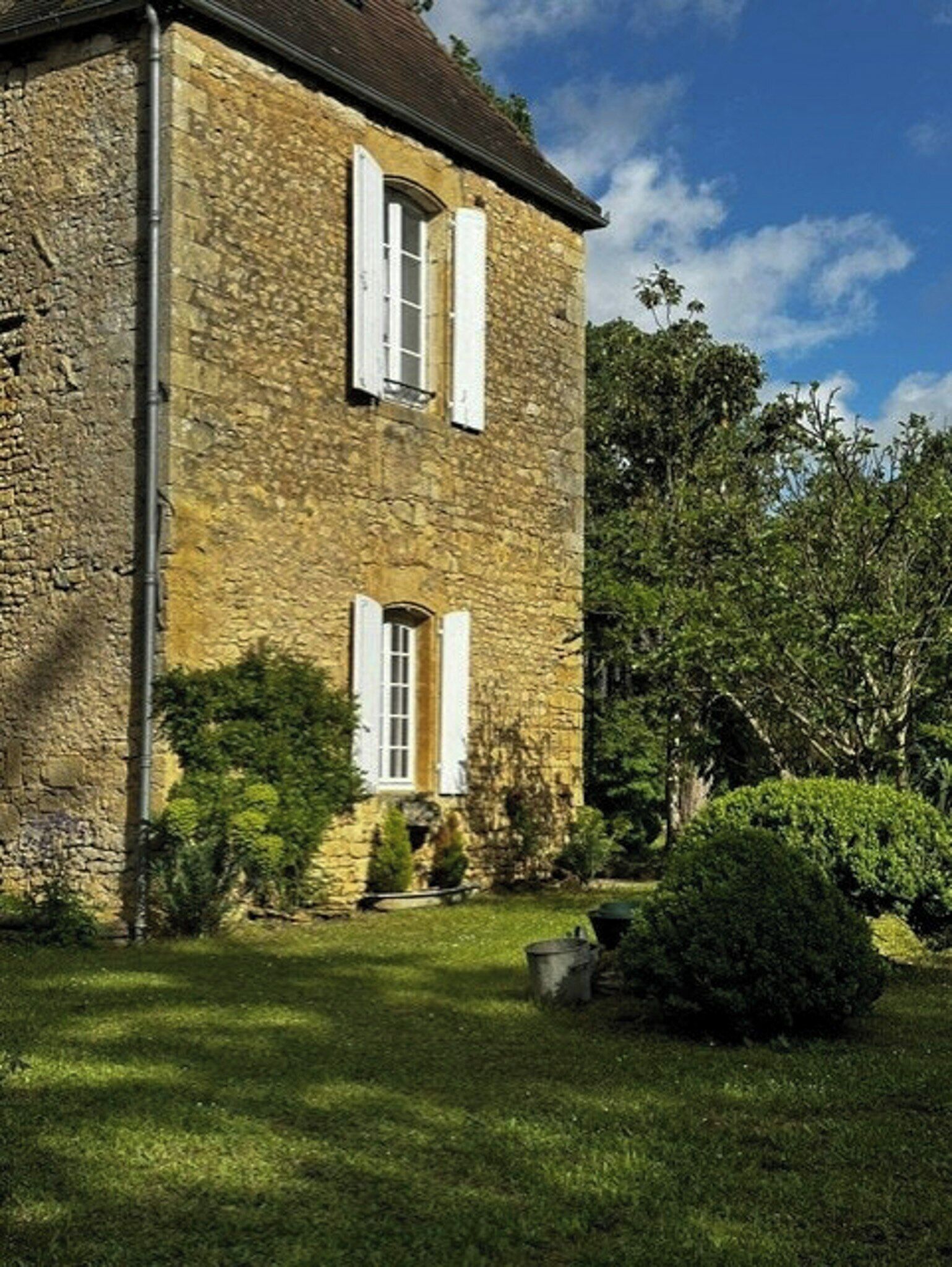 Un edificio de piedra con dos ventanas y un jardín bien cuidado.
