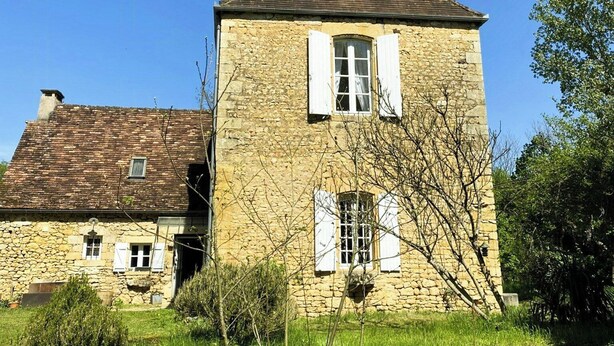 Un bâtiment en pierre doté d’un toit à deux versants, d’une cheminée et d’une petite fenêtre.