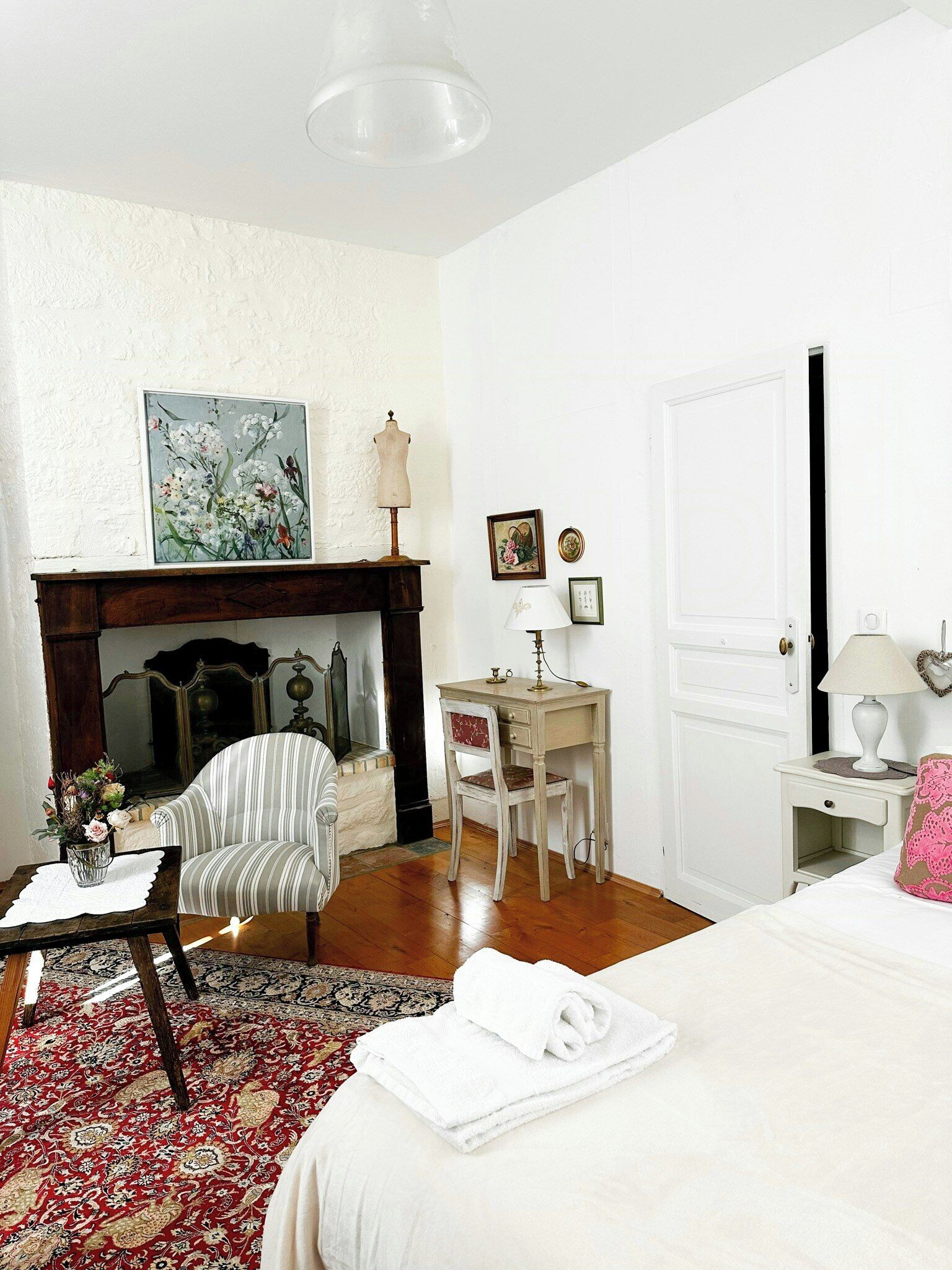 Una habitación con cama, escritorio, silla, chimenea y puerta.