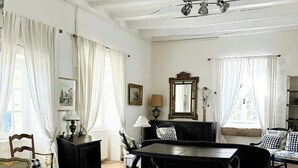 Un salon spacieux comprenant une table à manger, deux chaises, un canapé et un grand miroir.