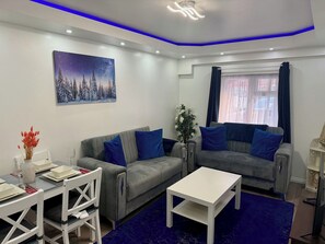 Ein modernes Wohnzimmer mit einem grauen Sofa, einem weißen Couchtisch und einem Gemälde von einem verschneiten Wald.