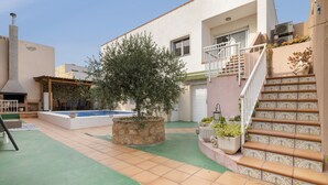 A courtyard with a swimming pool, a stone planter with a tree, and a staircase with decorative tiles.