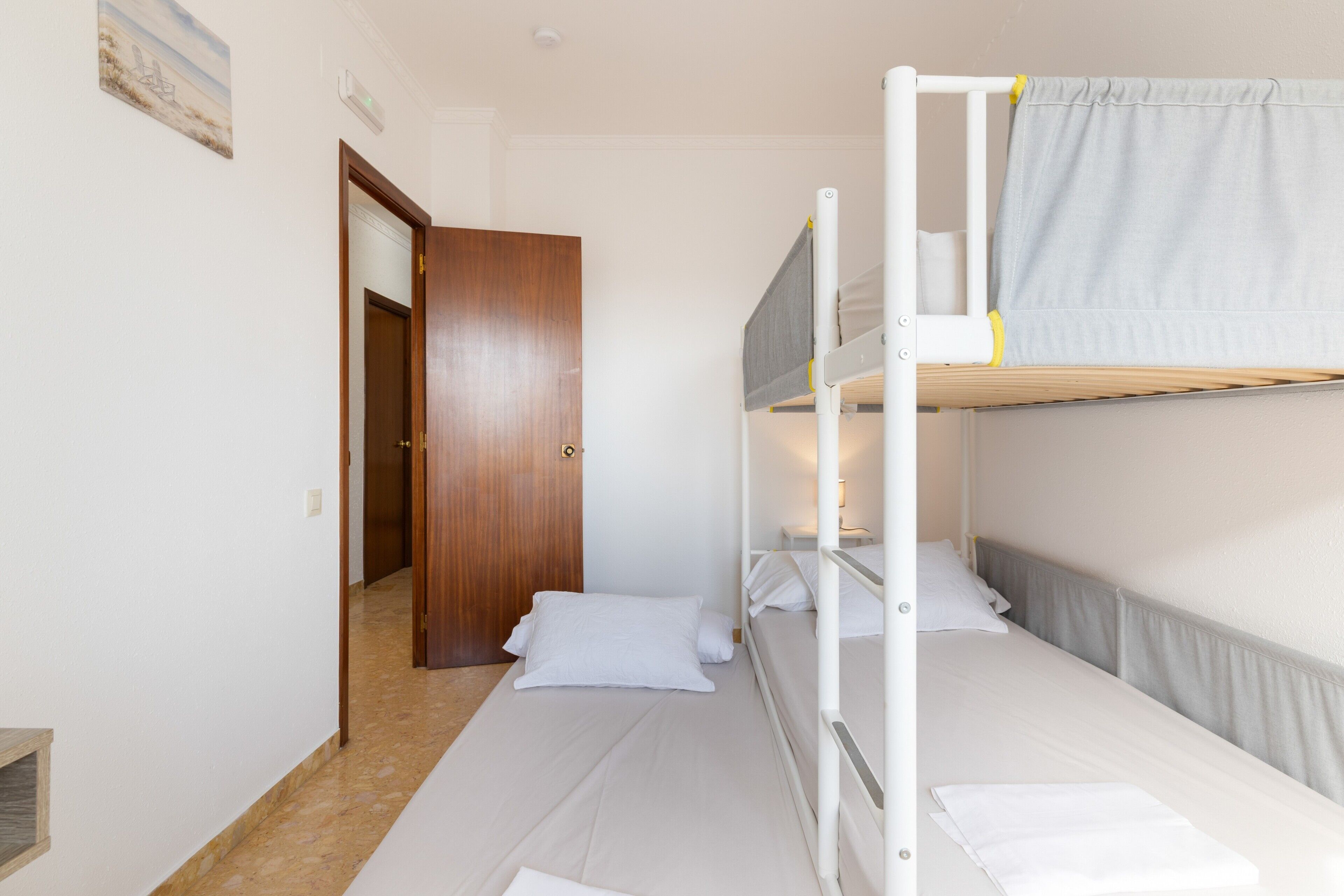 Een slaapkamer met stapelbed, een houten deur, een klein plankje en een lichtschakelaar aan de muur.
