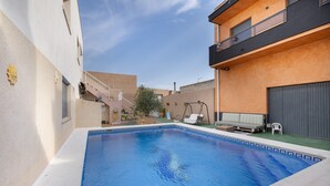 A swimming pool with a blue border, a staircase, and a small garden area with a swing set.