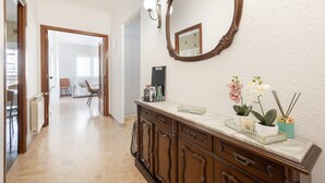 A hallway with a wooden cabinet, a mirror, and a potted plant.