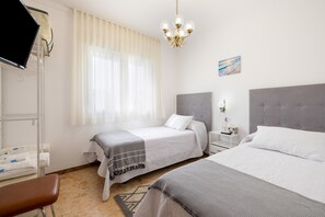 Une chambre d’hôtel avec deux lits, une télévision, une table de chevet avec une lampe et un tableau au mur.