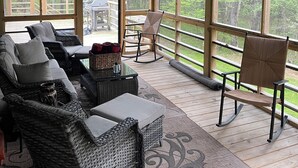 A covered outdoor seating area with wicker furniture, a ceiling fan, and a view of a wooded area. - Welcome to 'Legacy Lodge',' your ultimate Centre County PA cabin getaway! (Munson)