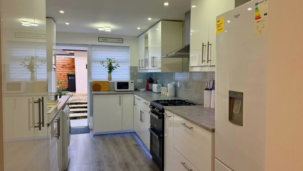 Una cocina moderna con gabinetes blancos, estufa, microondas y refrigerador.