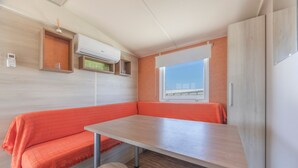 A compact room with a bench, a table, and a window with a view. - Bungalow 'Tranquilo Cerca De Roche' with Private Pool, Wi-Fi and Air Conditioning (Conil de la Frontera)