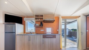A modern kitchen with a built-in refrigerator, wooden cabinets, and a window overlooking a backyard. - Bungalow 'Tranquilo Cerca De Roche' with Private Pool, Wi-Fi and Air Conditioning (Conil de la Frontera)
